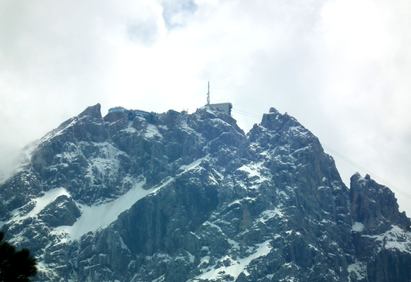 Gipfel eines schneebedeckten Berges mit einer Antennenanlage und einer Seilbahnstation auf der Zugspitze