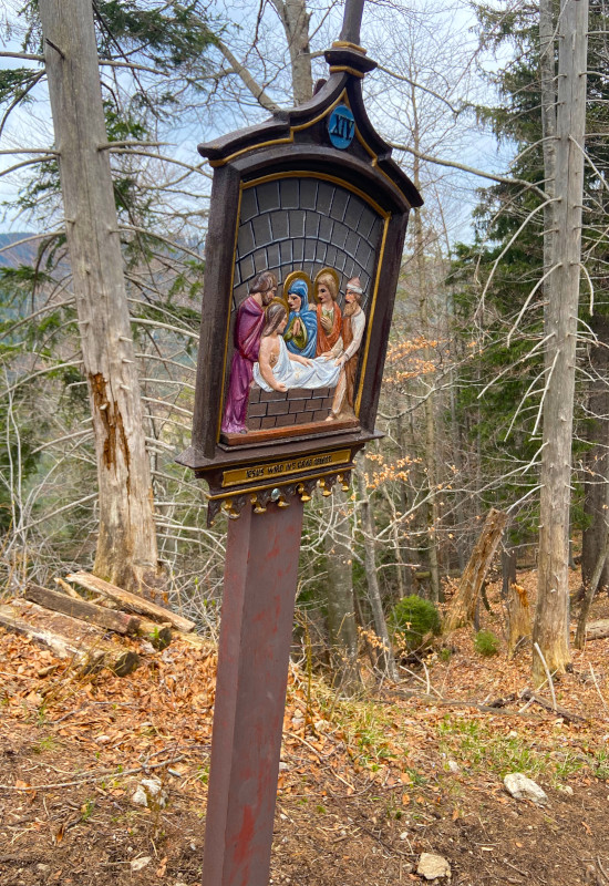 Religiöse Tafel im Wald mit Darstellung einer Szene.