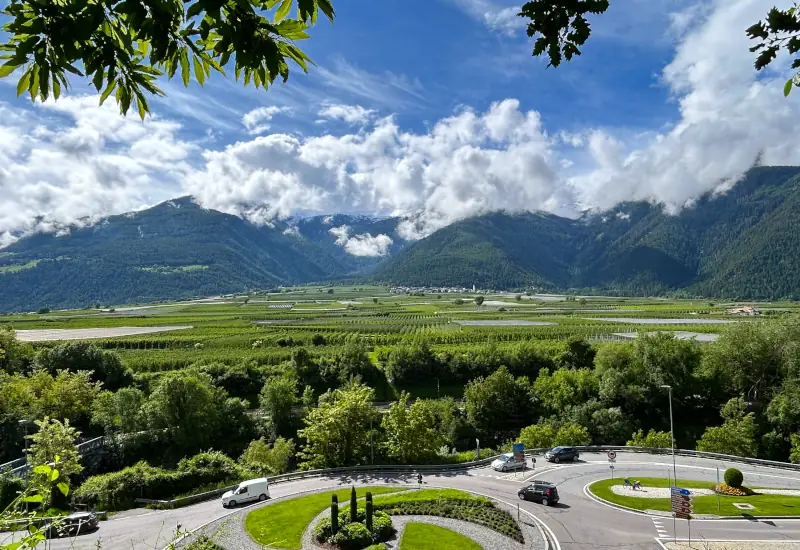 Berglandschaft mit Wolken, Weinbergen und Rundstraße.