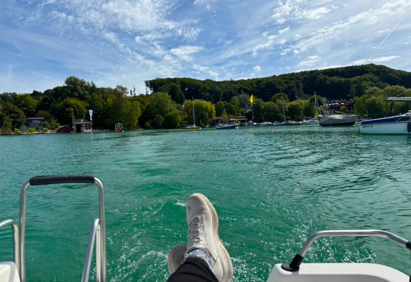 Füße auf einem Boot, Blick auf den grünen See.